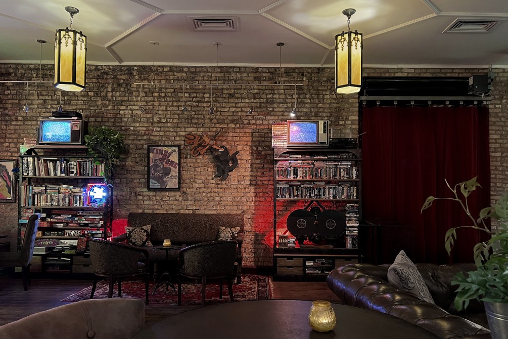 Interior of the Music Box Lounge with exposed brick wall, fancy lighting, eclectic furniture and CRT television sets.