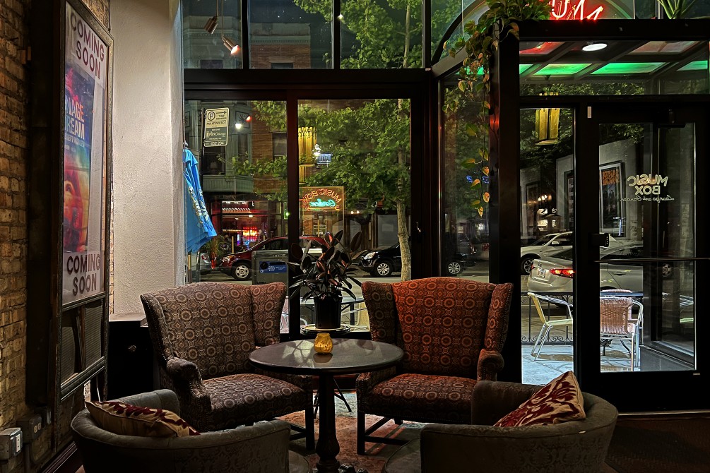 Dim lit nook in the Music Box Lounge looking through large glass windows toward the street.