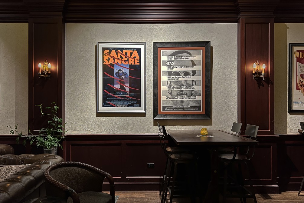 Interior of the Music Box Lounge with framed film posters, fine woodwork and industrial draft tables and stools.